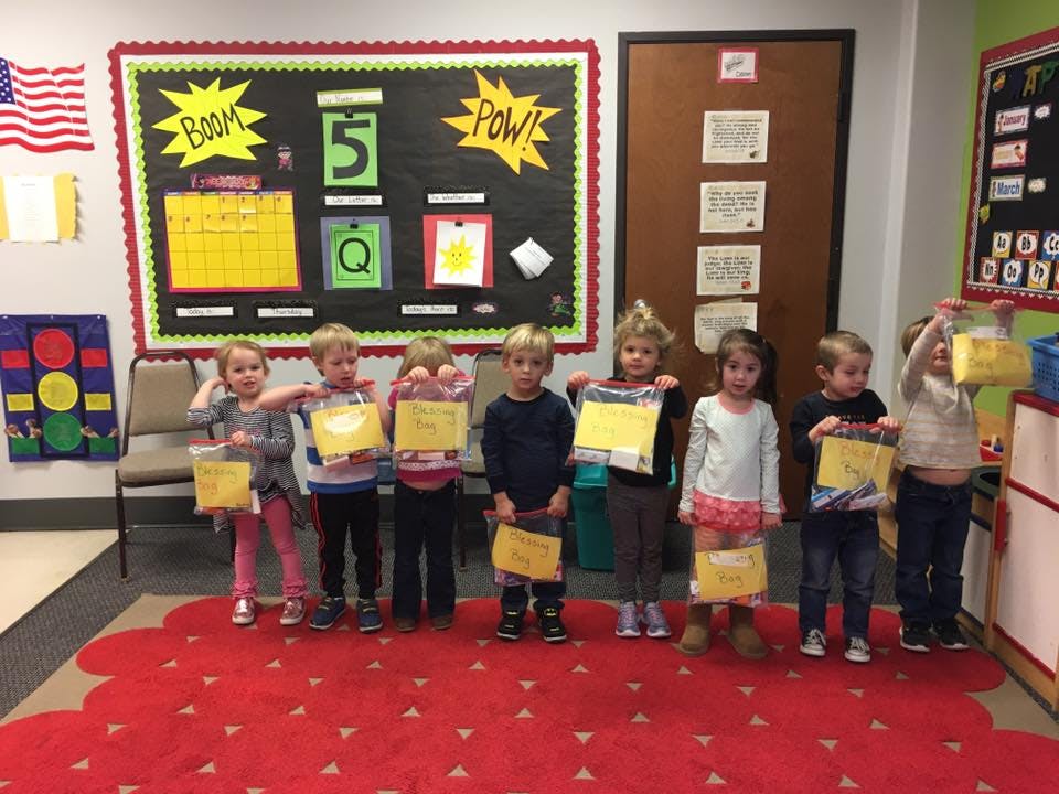 Children standing in a classroom holding up yellow papers