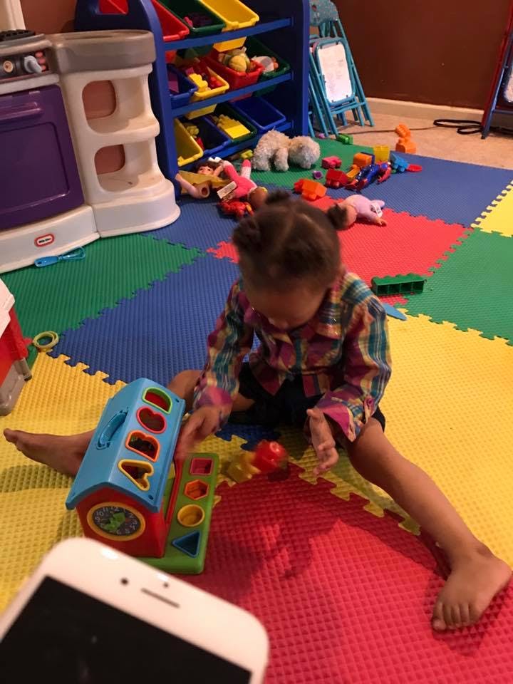 Child playing with a shape sorter toy on a colorful mat
