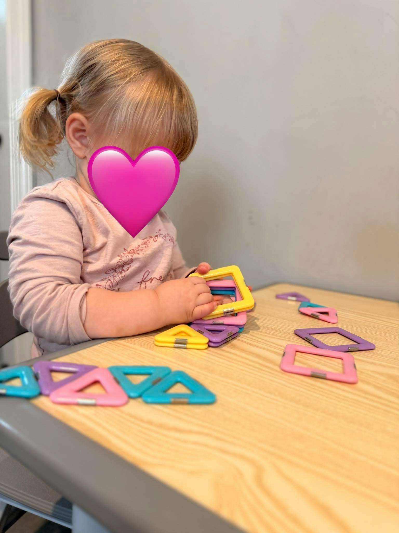 Child playing with colorful magnetic tiles on a table