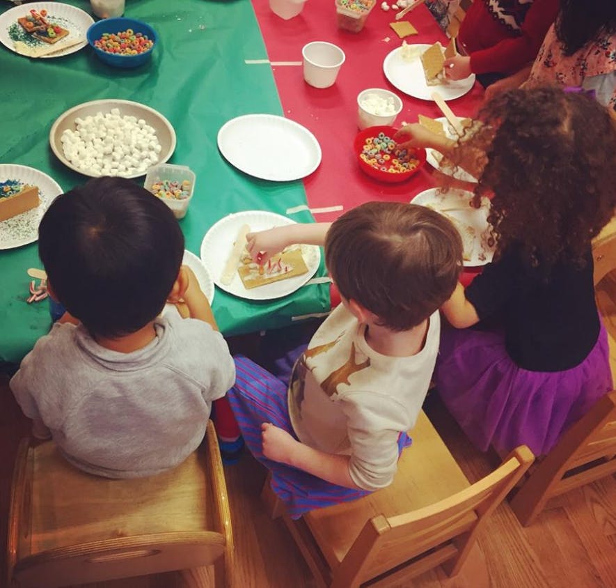 Children decorating gingerbread houses at a table