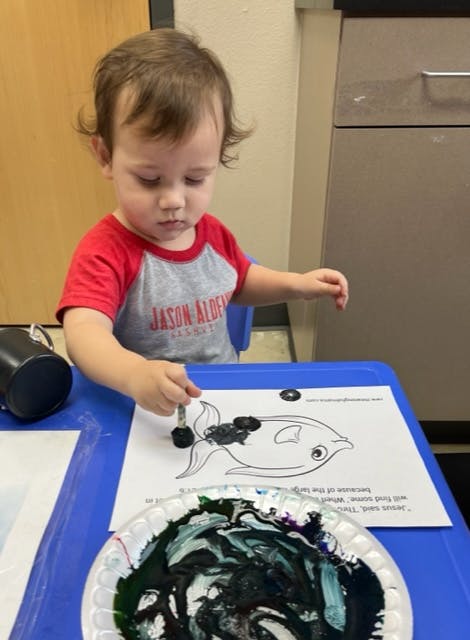 Child painting a fish outline on paper
