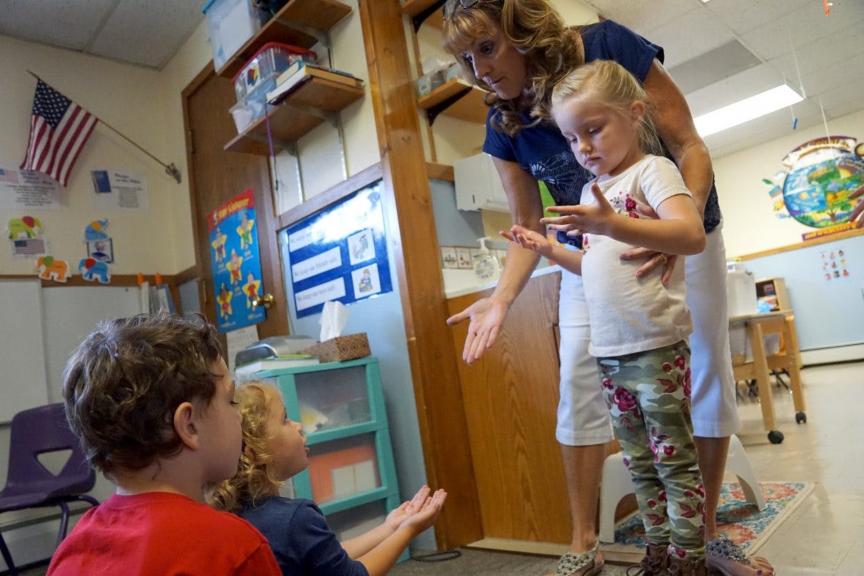 Adult and three children interacting in a classroom