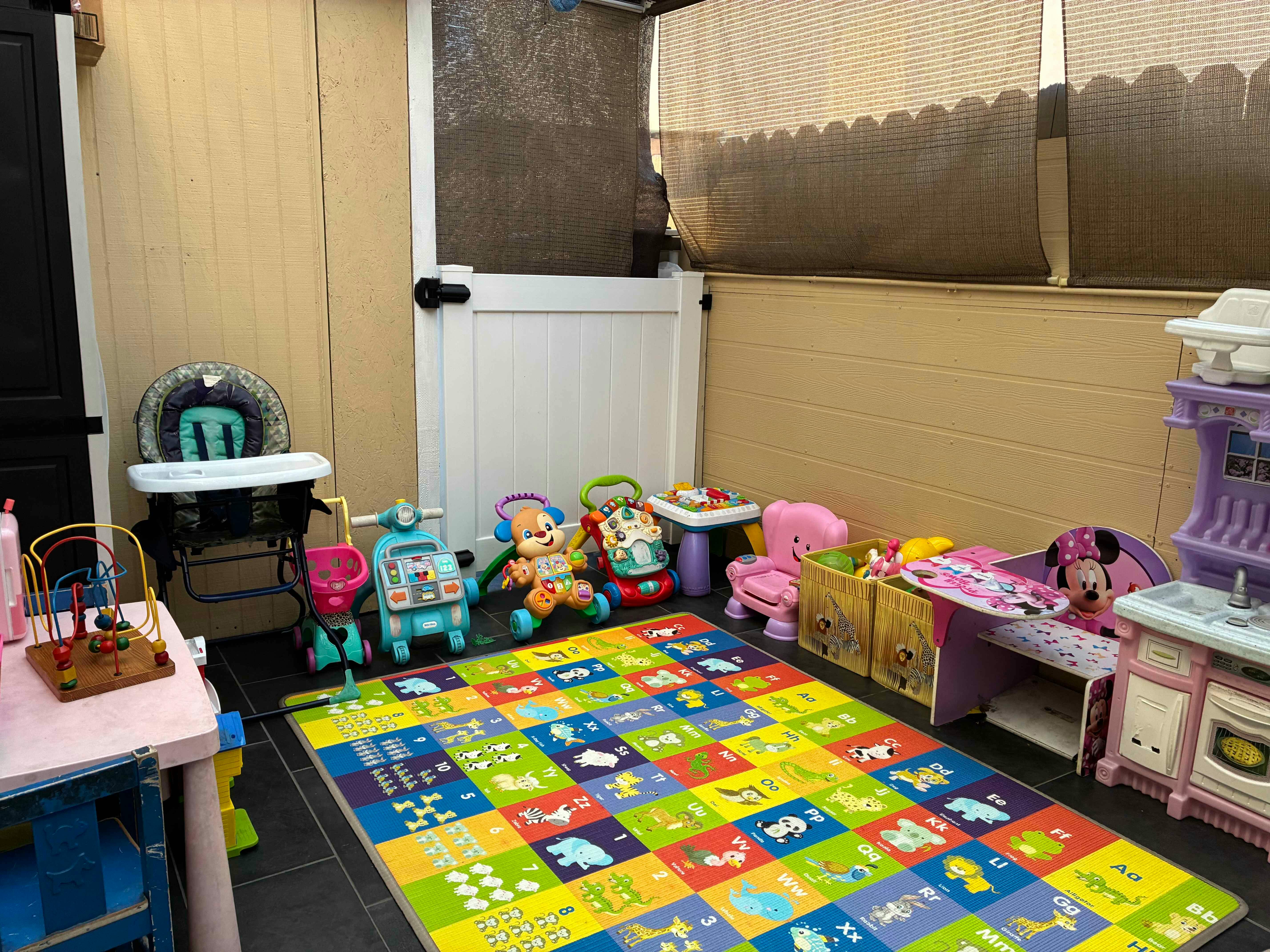 Child's play area with an alphabet mat, toys, and a high chair