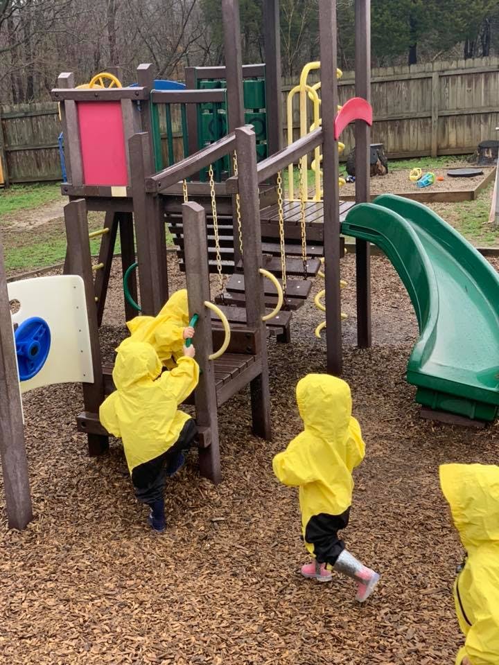 Children in yellow raincoats playing on a playground structure