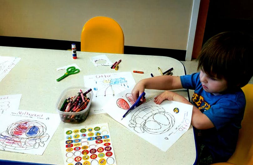 Child cutting paper with scissors at a table