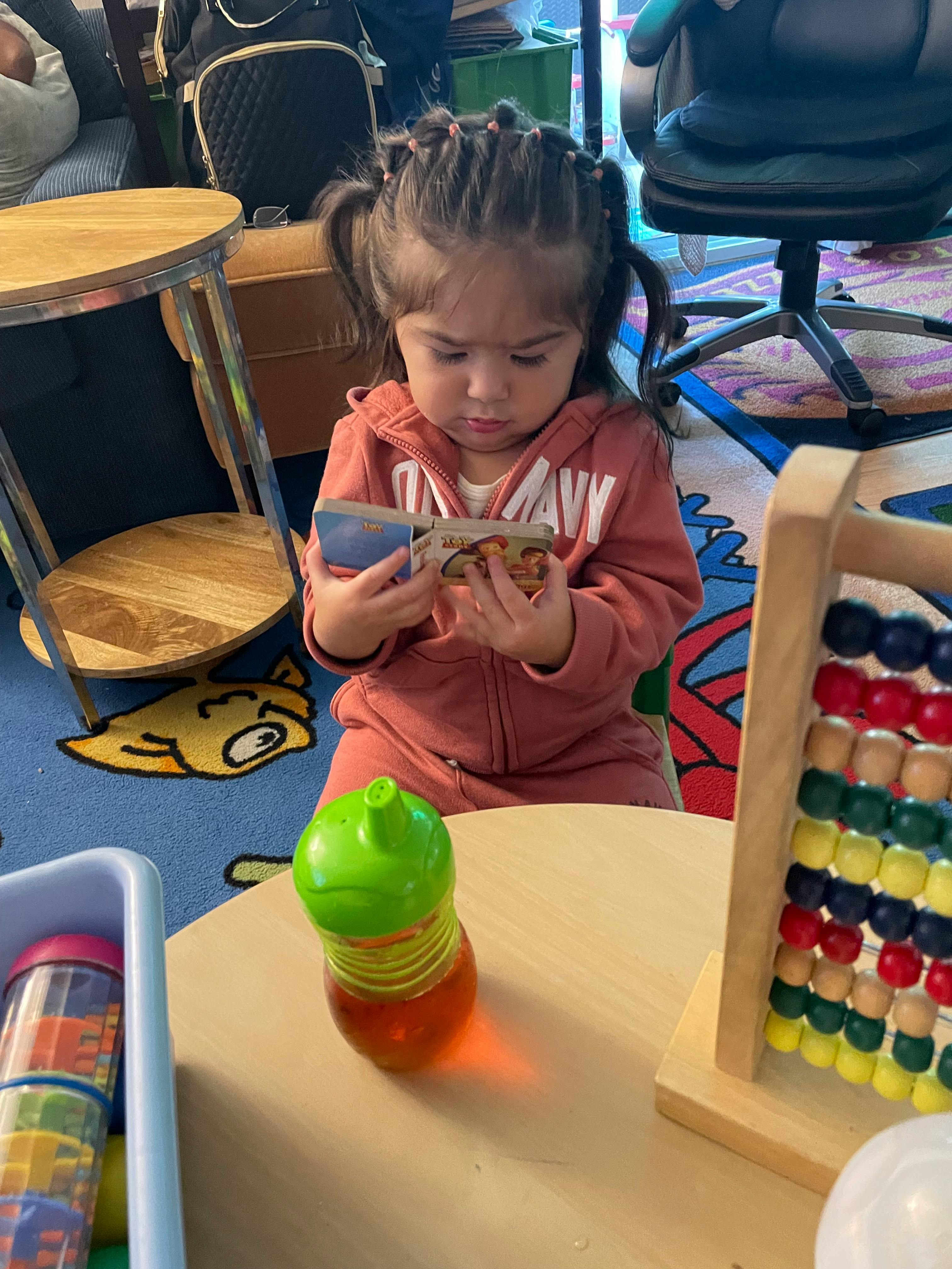 Child sitting on the floor looking at a small book