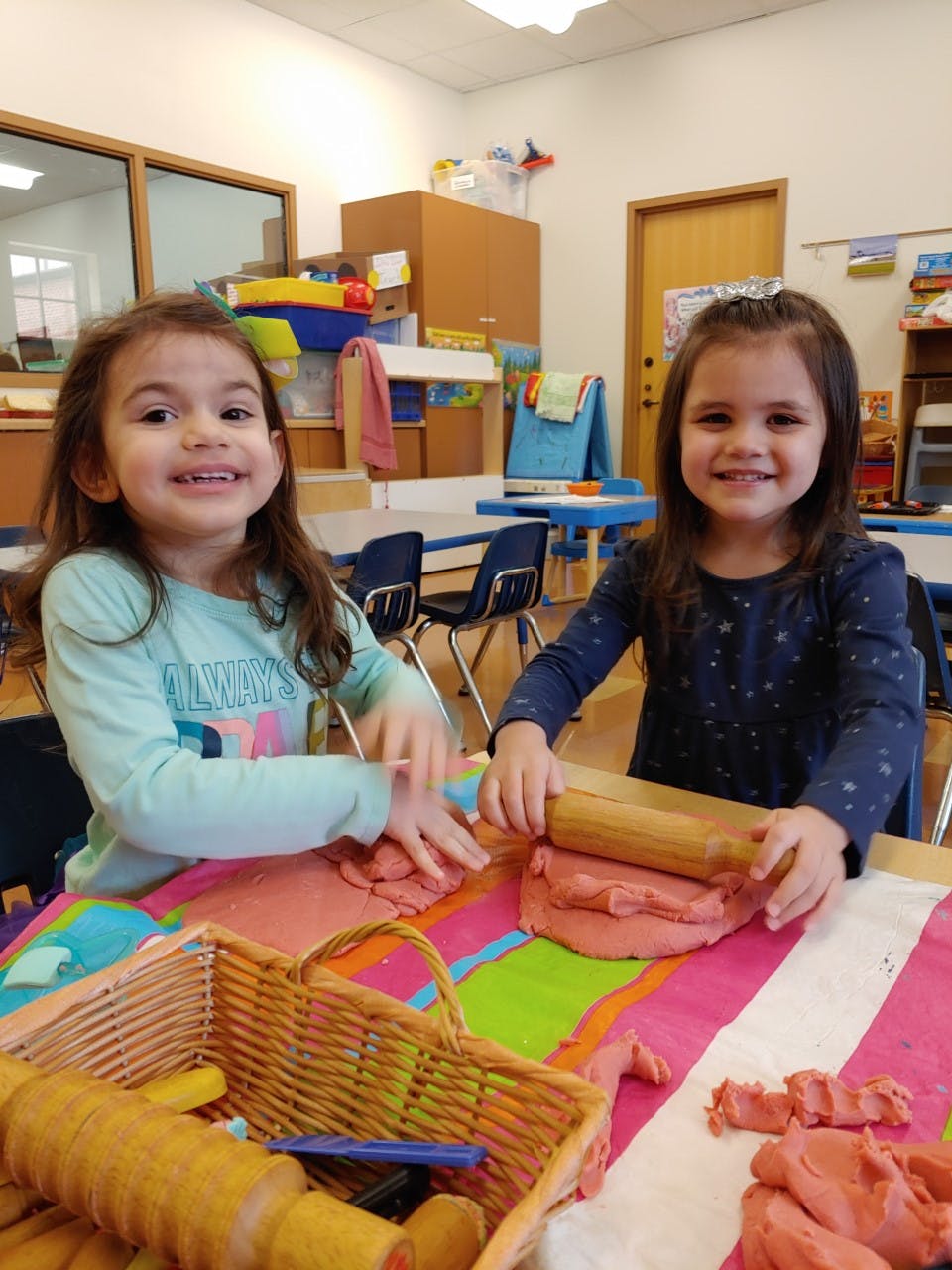 Two children playing with modeling clay in a classroom