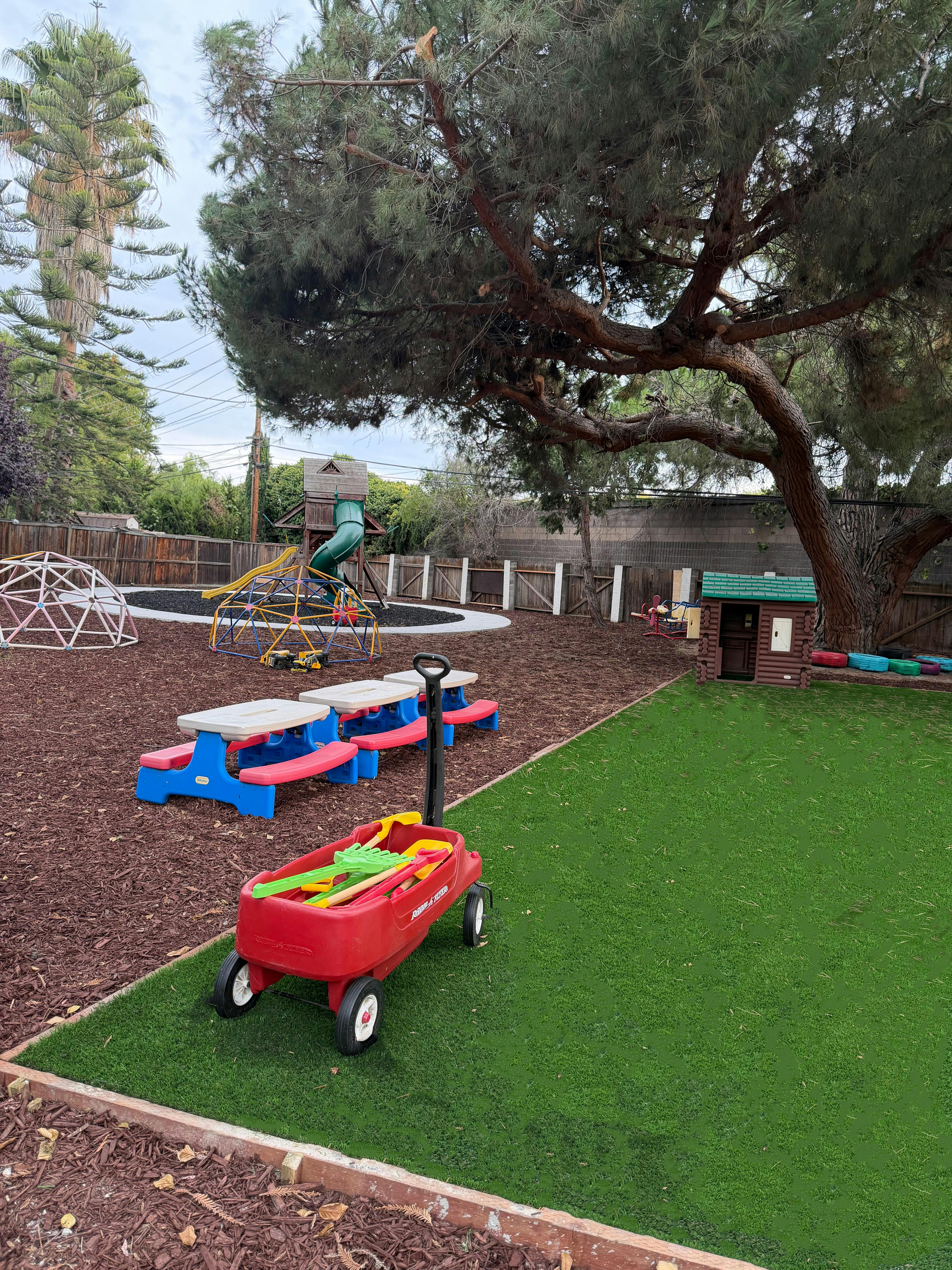 Playground with a red wagon, picnic tables, and play structures