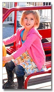 Child sitting on red playground equipment