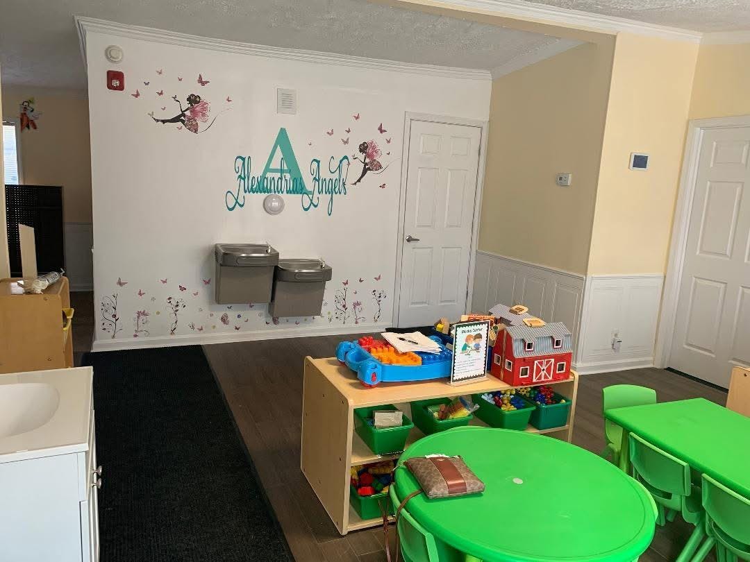 Classroom with small green tables and storage unit with toys