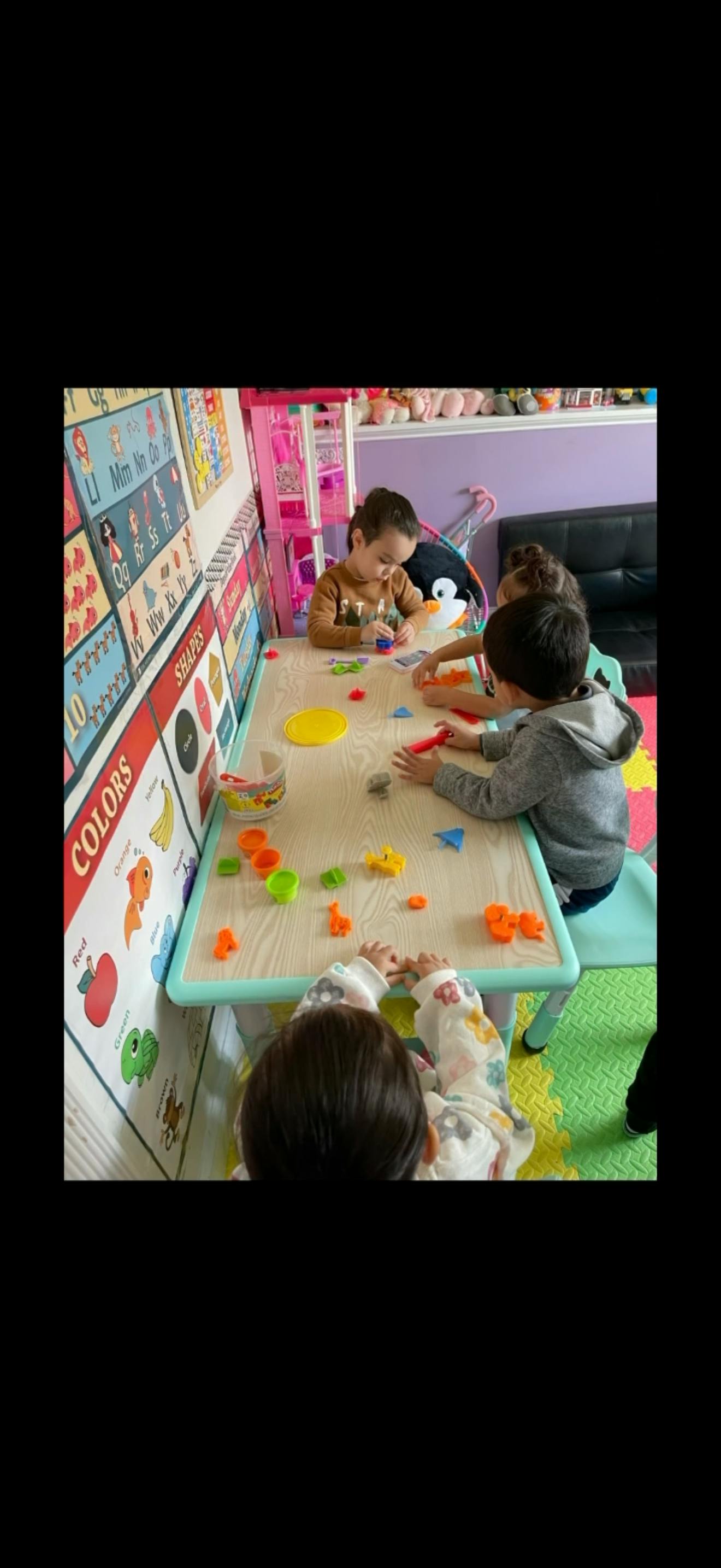 Children playing with clay at a table in a classroom