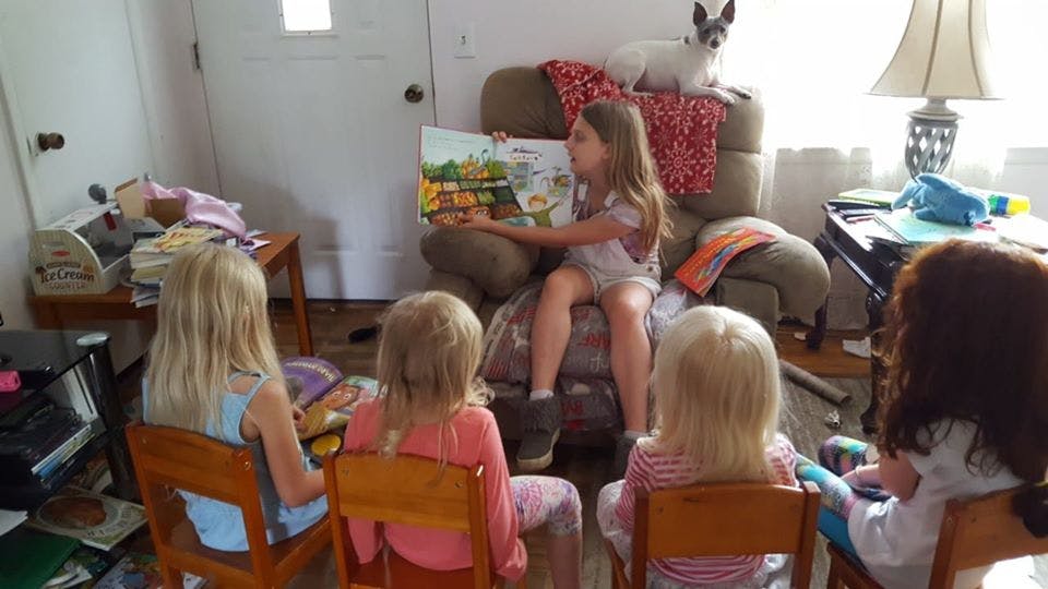 Child reading a book to other children