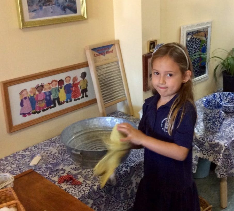 Child washing clothes in a basin with a washboard