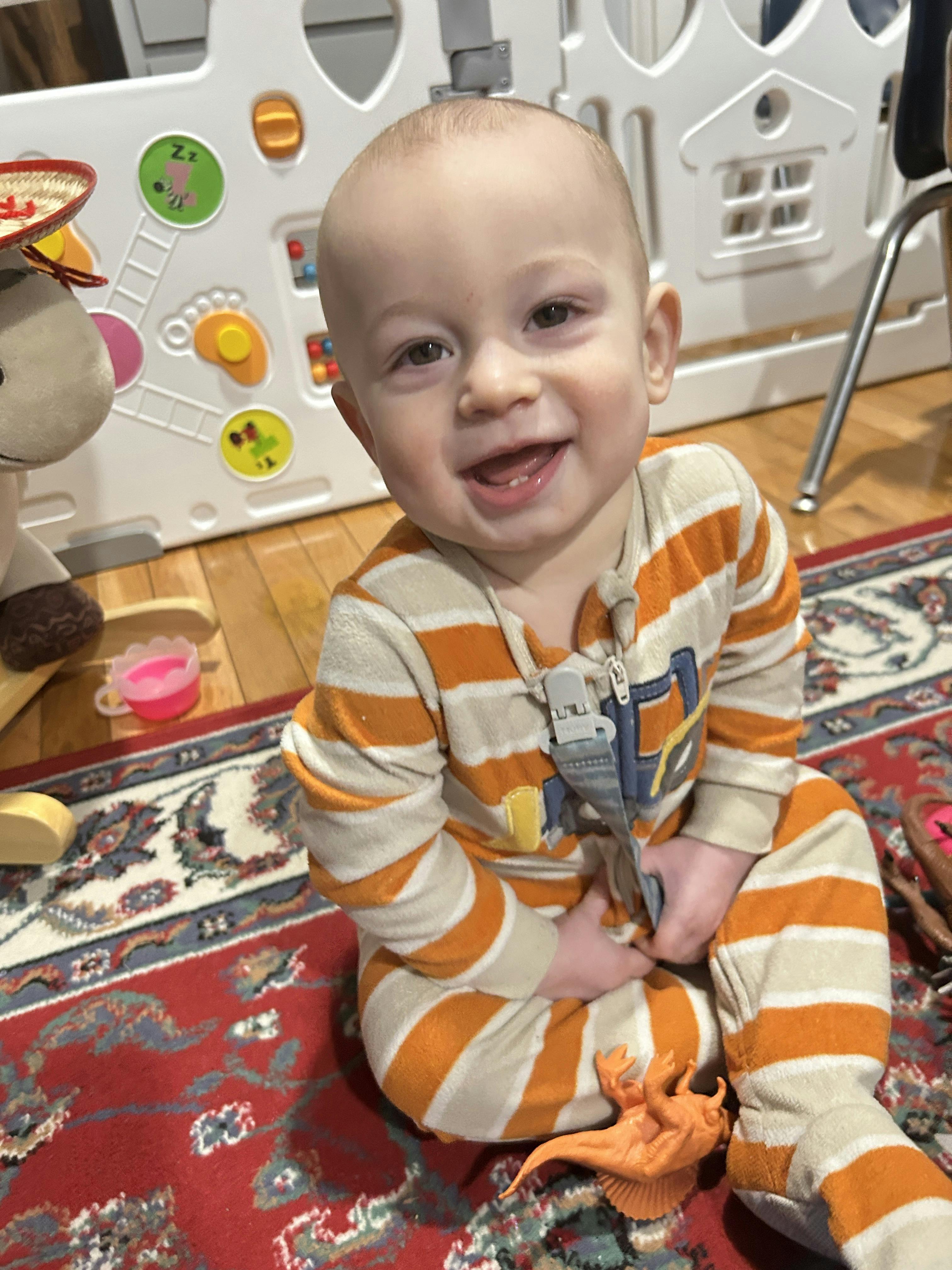 Child in striped pajamas sitting on a rug