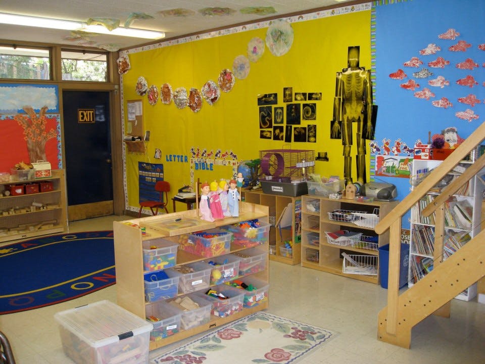 Classroom with colorful walls, shelves of toys, and a staircase