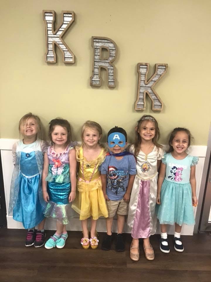Six children in costumes standing in a row