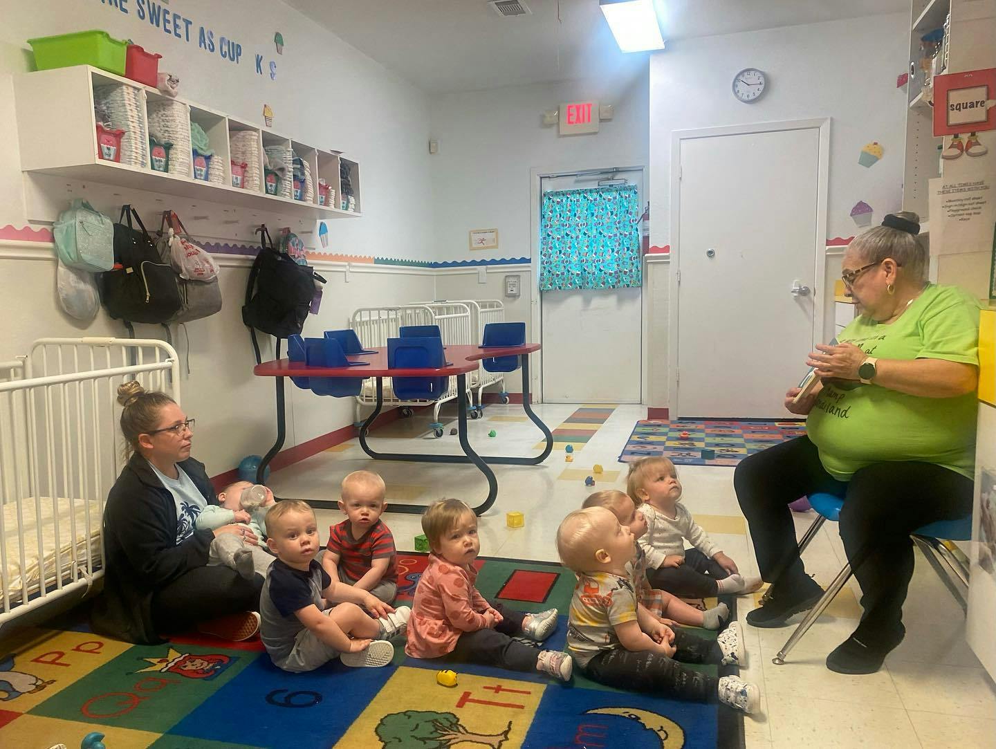 Adults and children sitting on a rug in a classroom