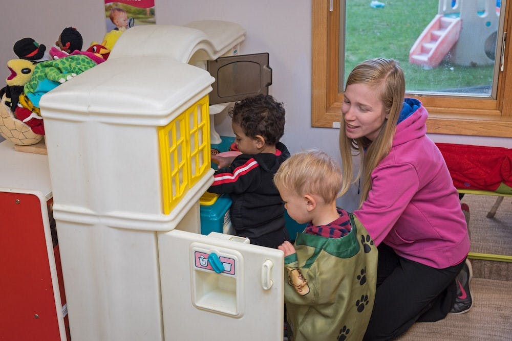Person and two children playing with a toy kitchen