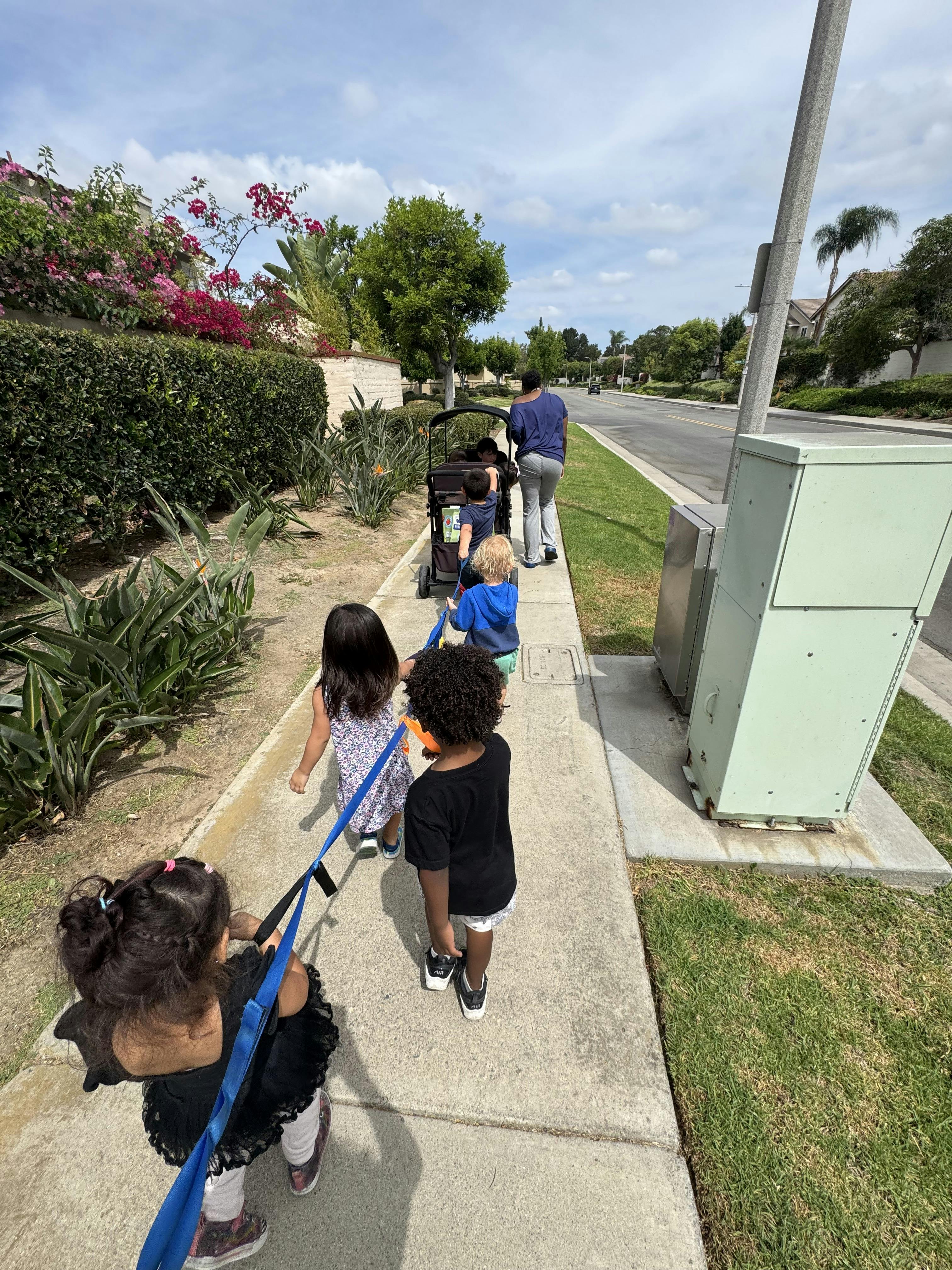 Group of children holding onto a walking rope on a sidewalk