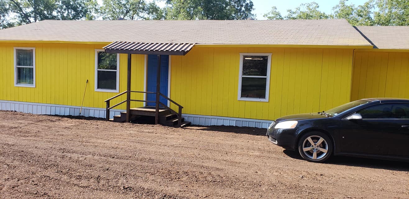 Yellow building with blue door and black car parked in front