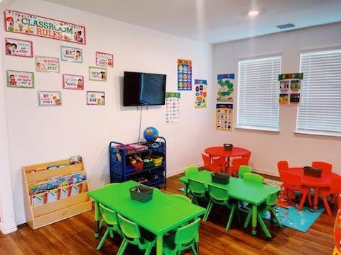 Classroom with small green and red tables and chairs, wall decorations