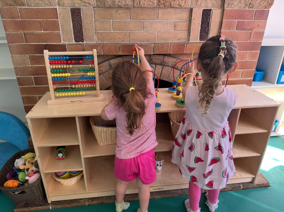 Two children playing with toys on a shelf in a classroom