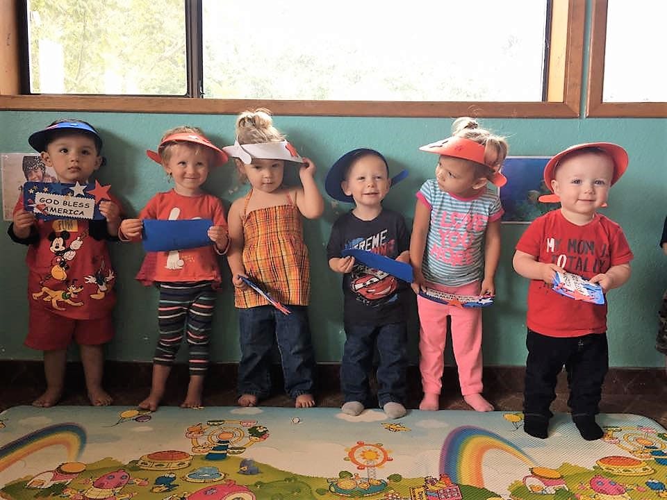 Six children standing in a row, some holding small items