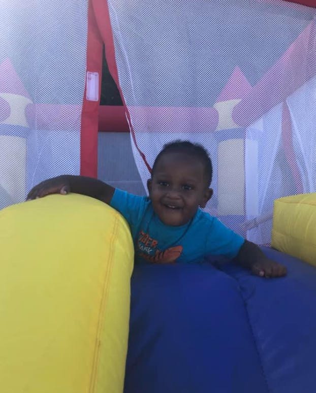 Child in a blue shirt playing in an inflatable bounce house