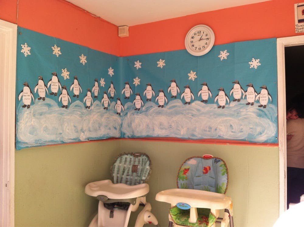 Wall mural with penguins on ice and snowflakes, two high chairs below