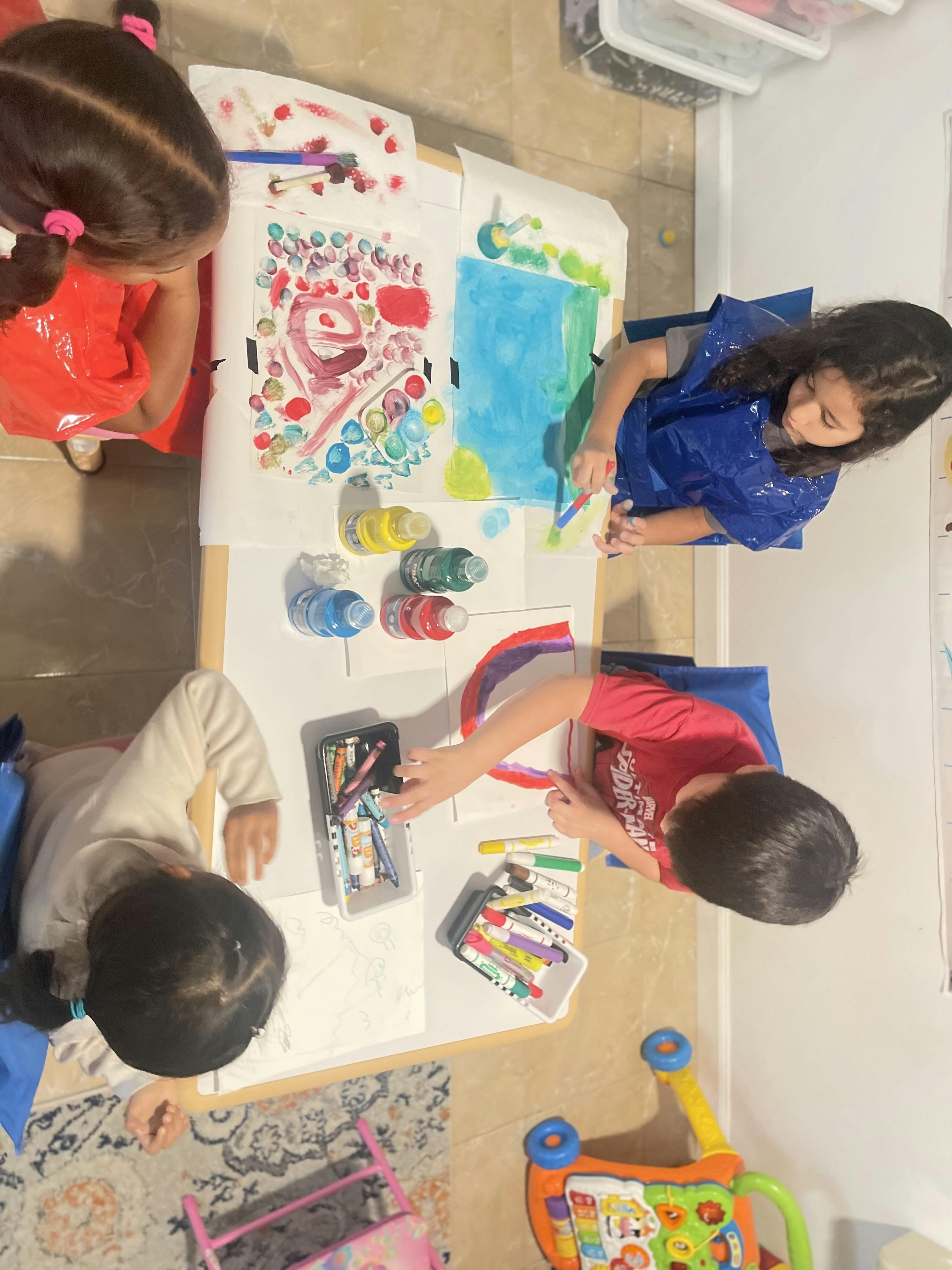 Three children painting and drawing at a table
