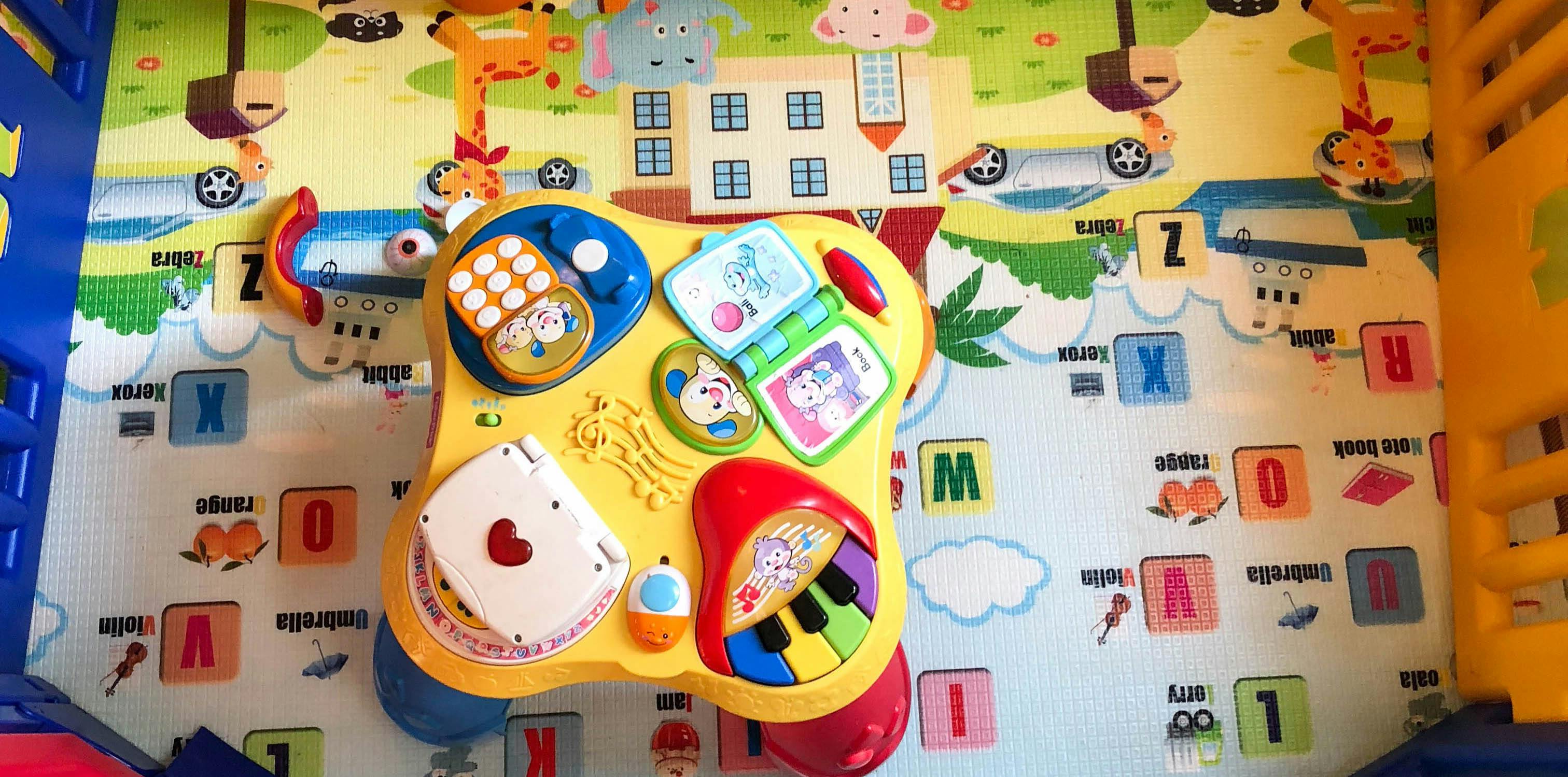 Yellow activity table for a child on a colorful playmat