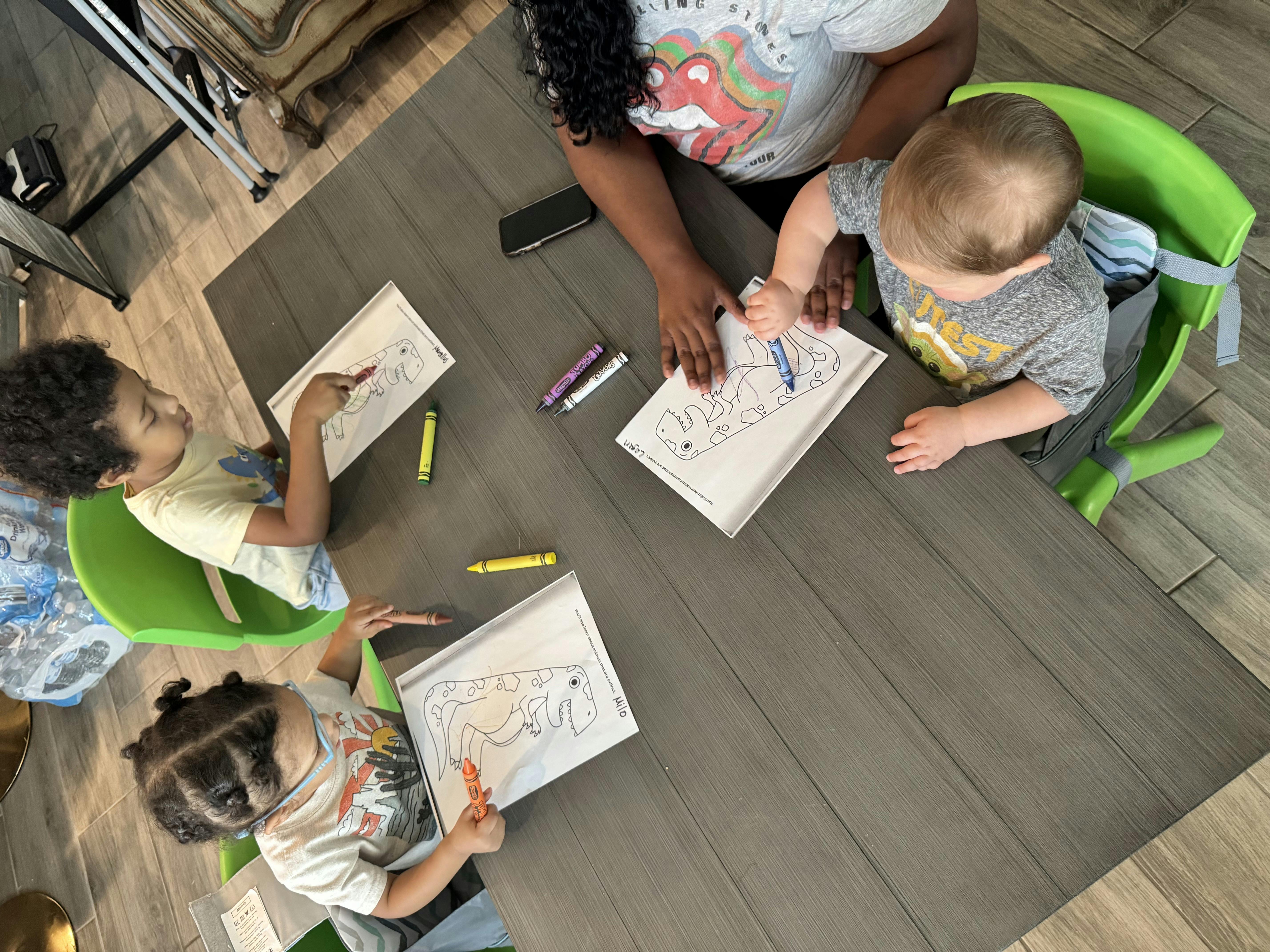 Person and three children coloring at a table