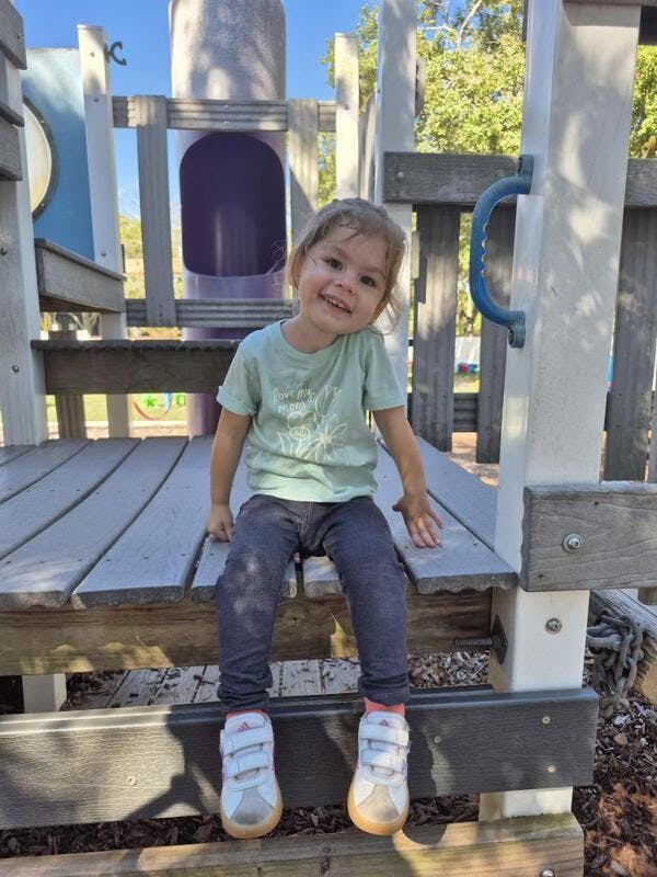 Child sitting on a wooden playground structure