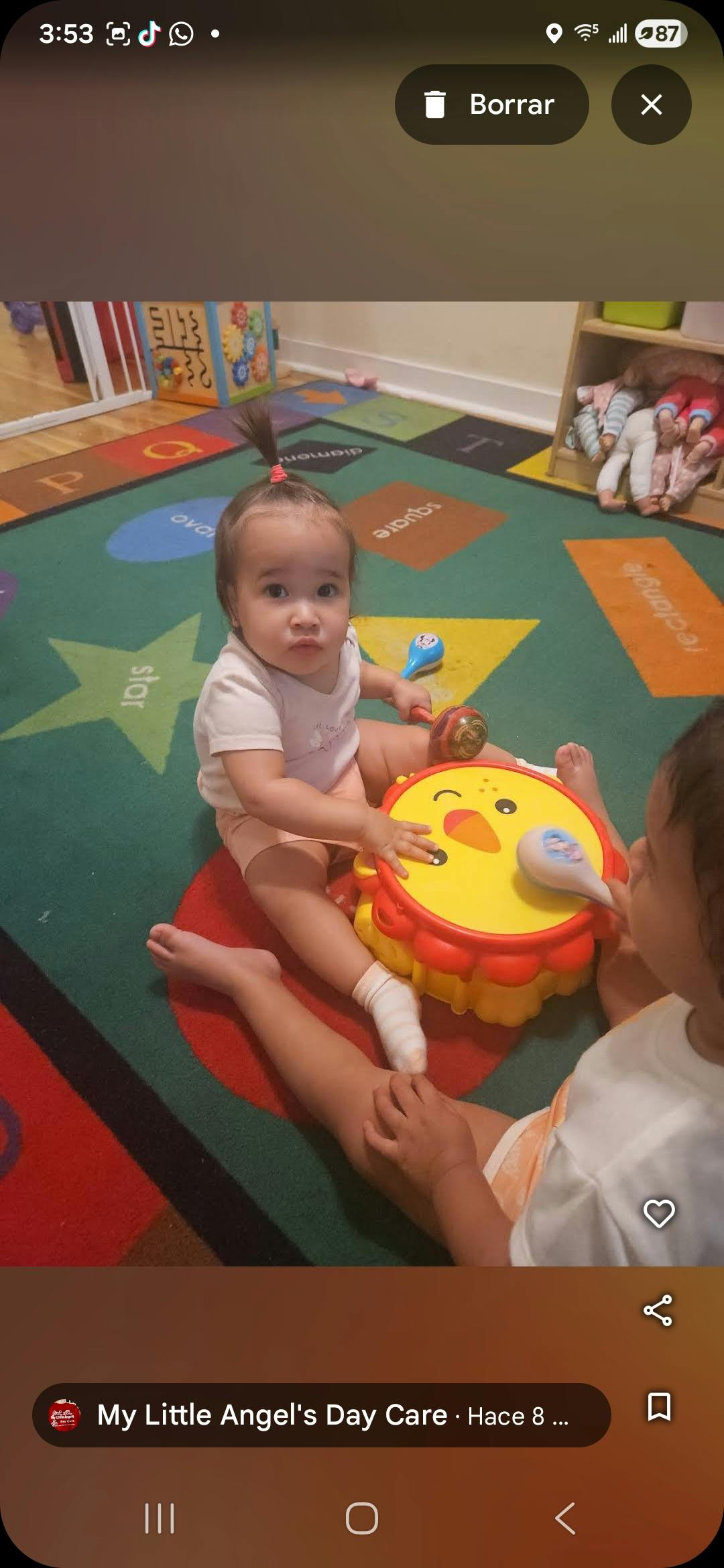 Child playing with a toy drum, another child next to them