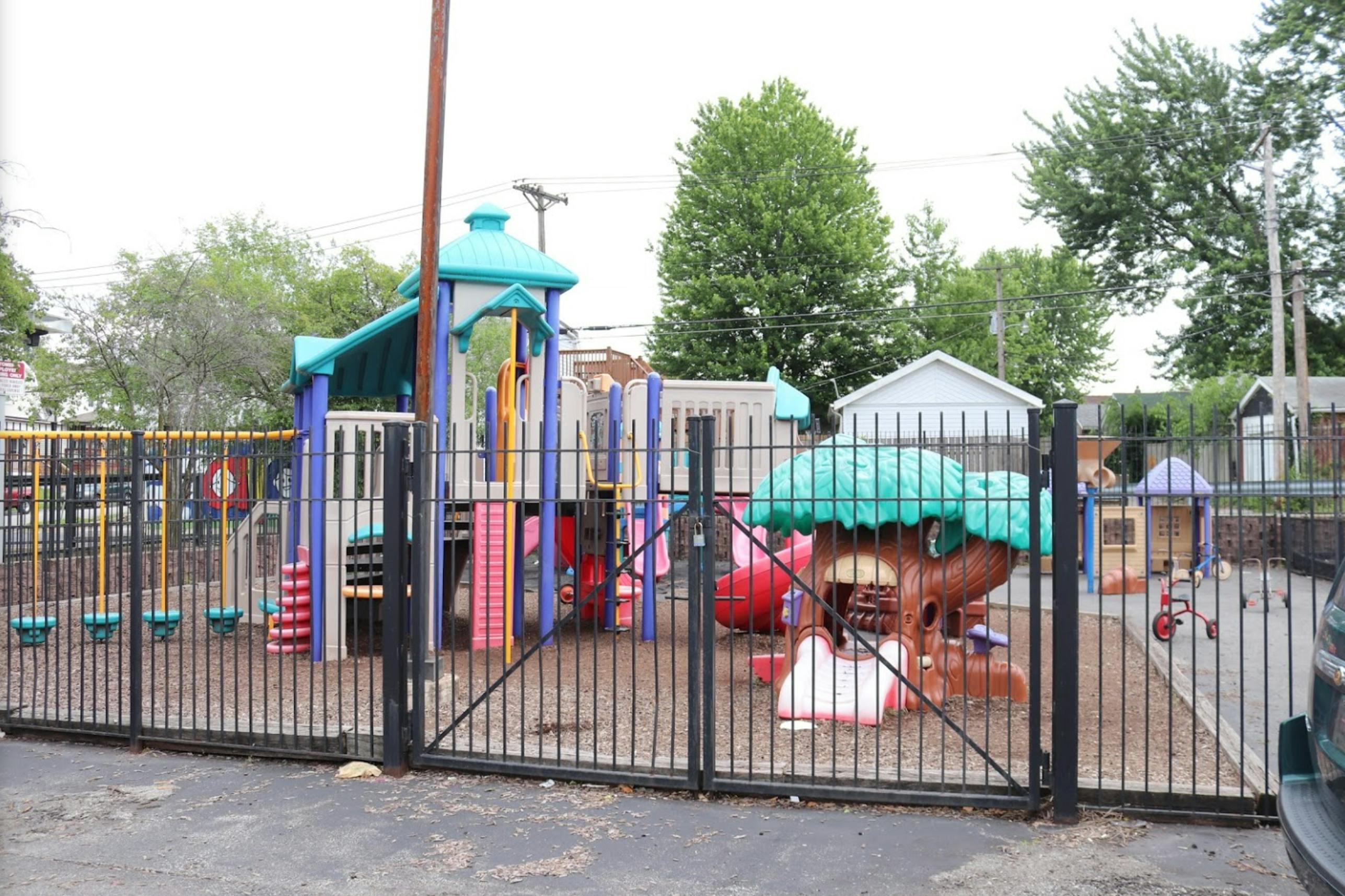 Outdoor playground with slides, swings, and play structures behind a fence