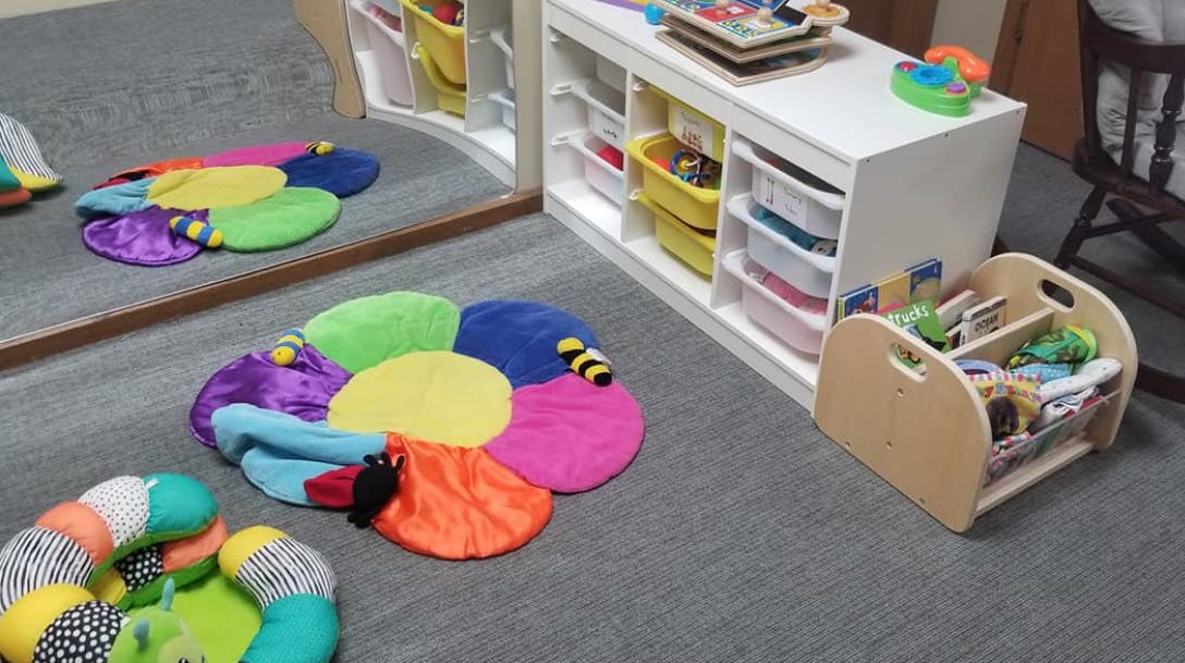 Colorful play mat on a gray carpeted floor in a room with storage shelves