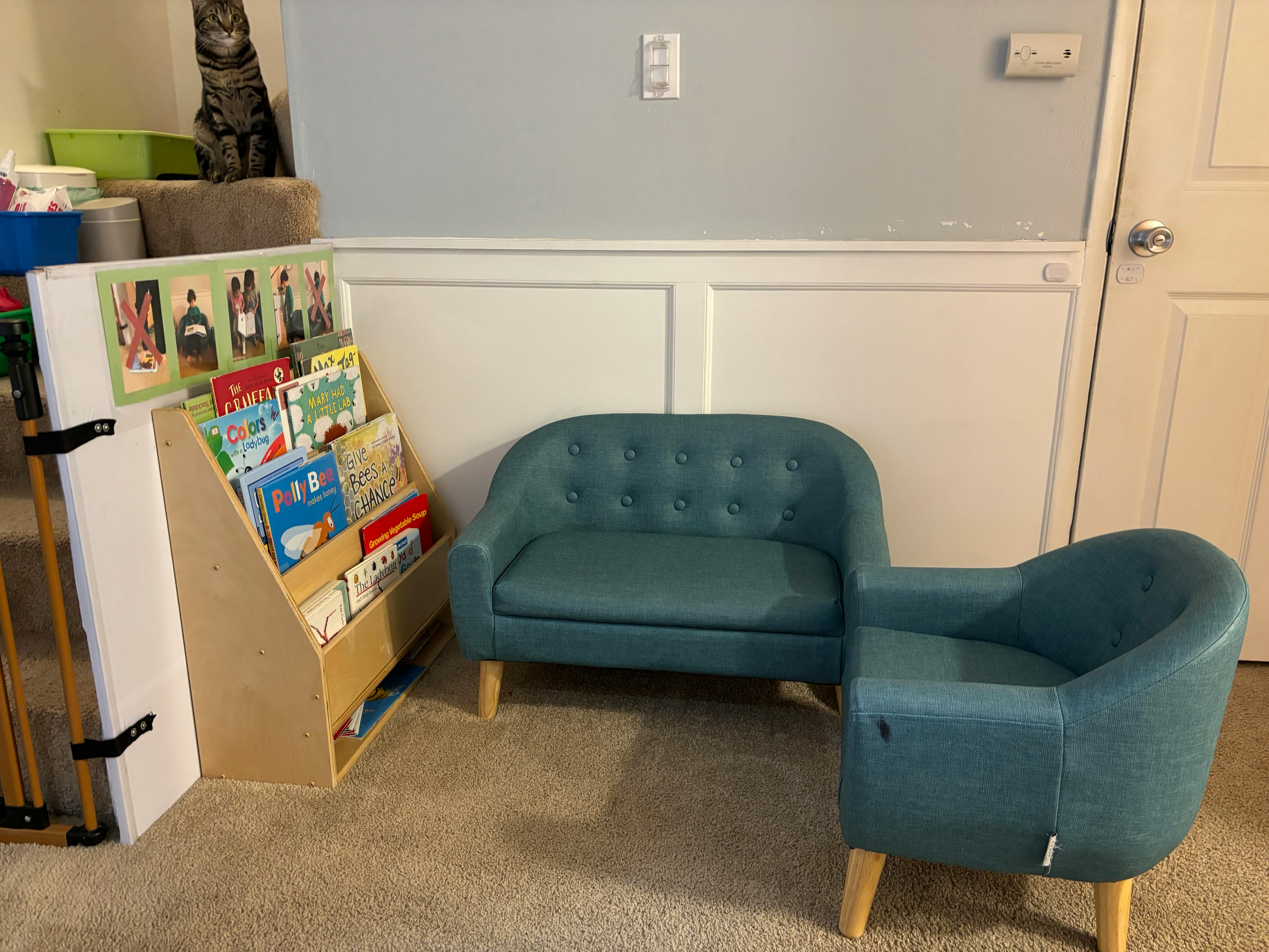 Small blue sofa and armchair next to a wooden book display