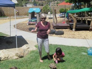 Adult and child on grass with playground in background