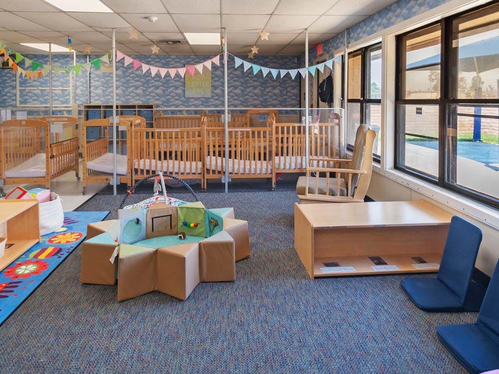 Cribs, playmat, and rocker in a daycare room