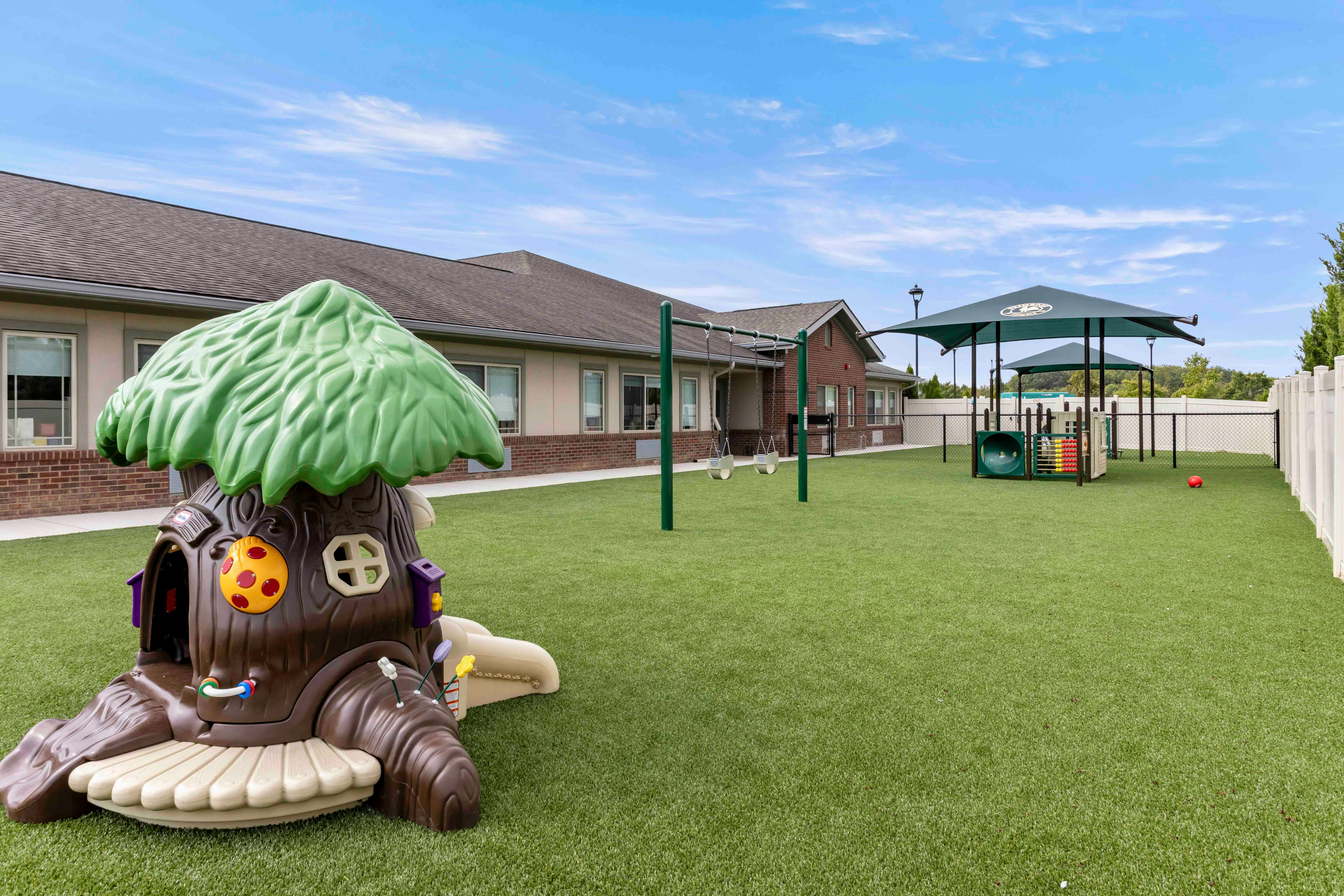 Playground with a treehouse structure, swings, and other play equipment