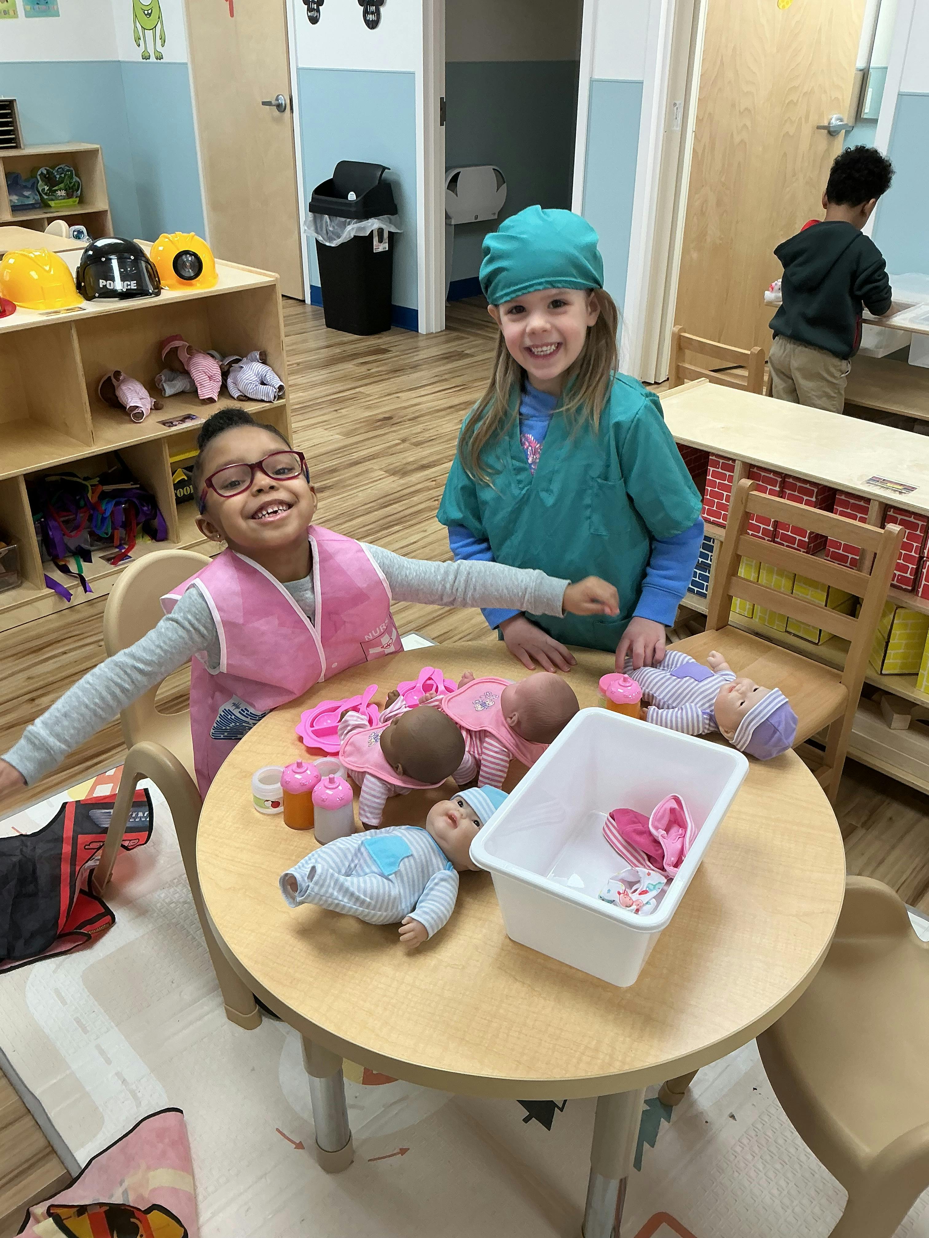Two children dressed up playing with baby dolls at a table
