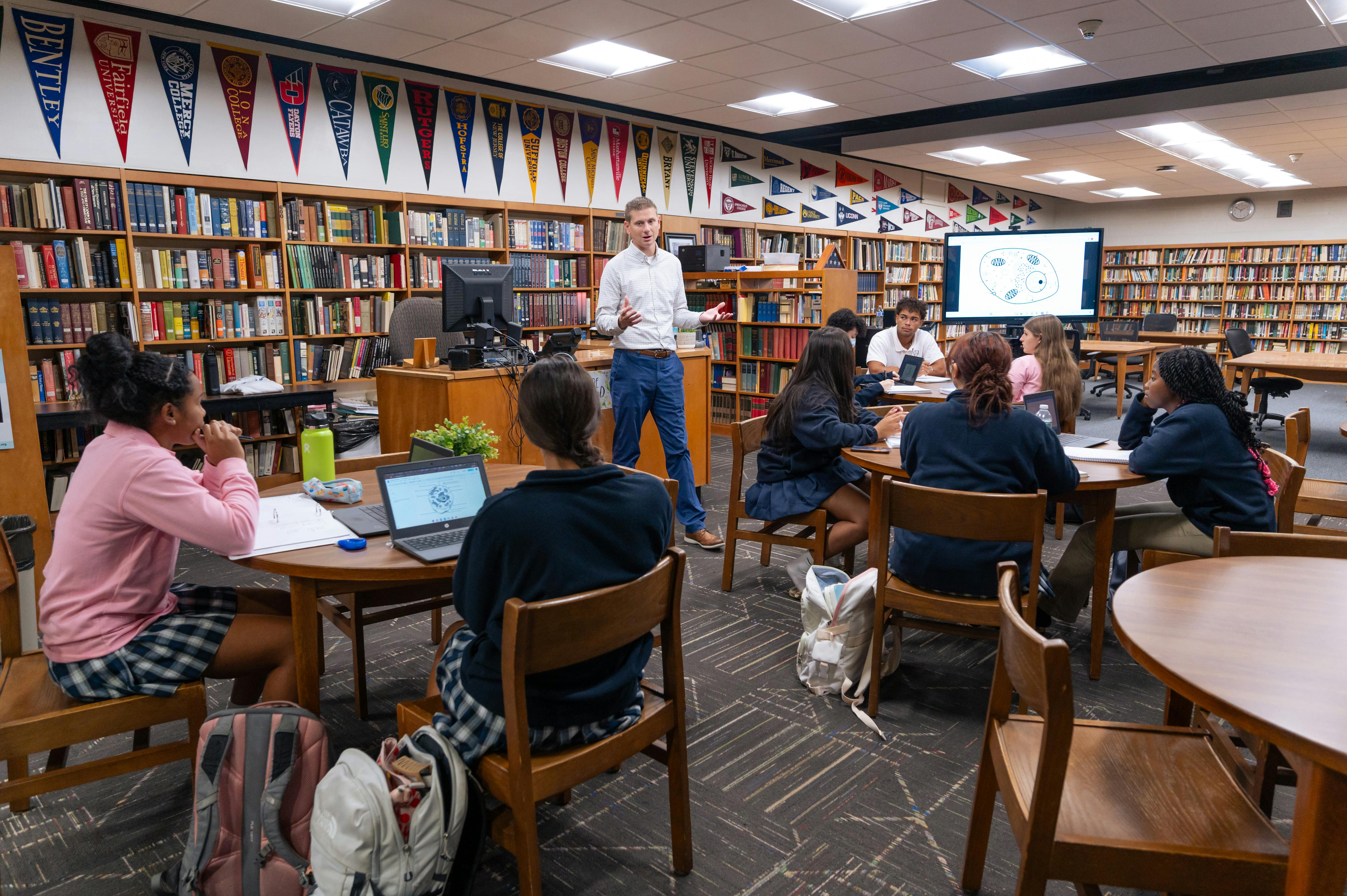 Adult speaking to a group of teens in a library