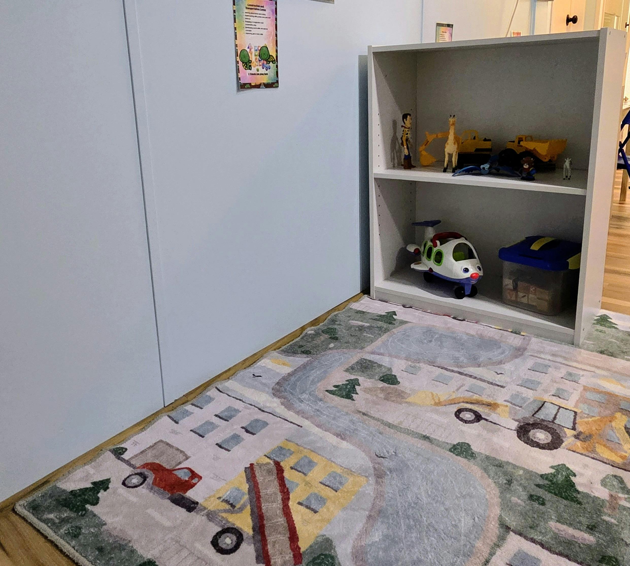 Playroom with a toy airplane, giraffe, and excavator on a shelf above a play rug