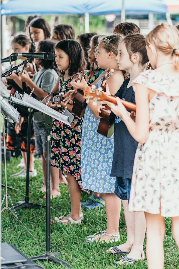 Children playing ukuleles outdoors