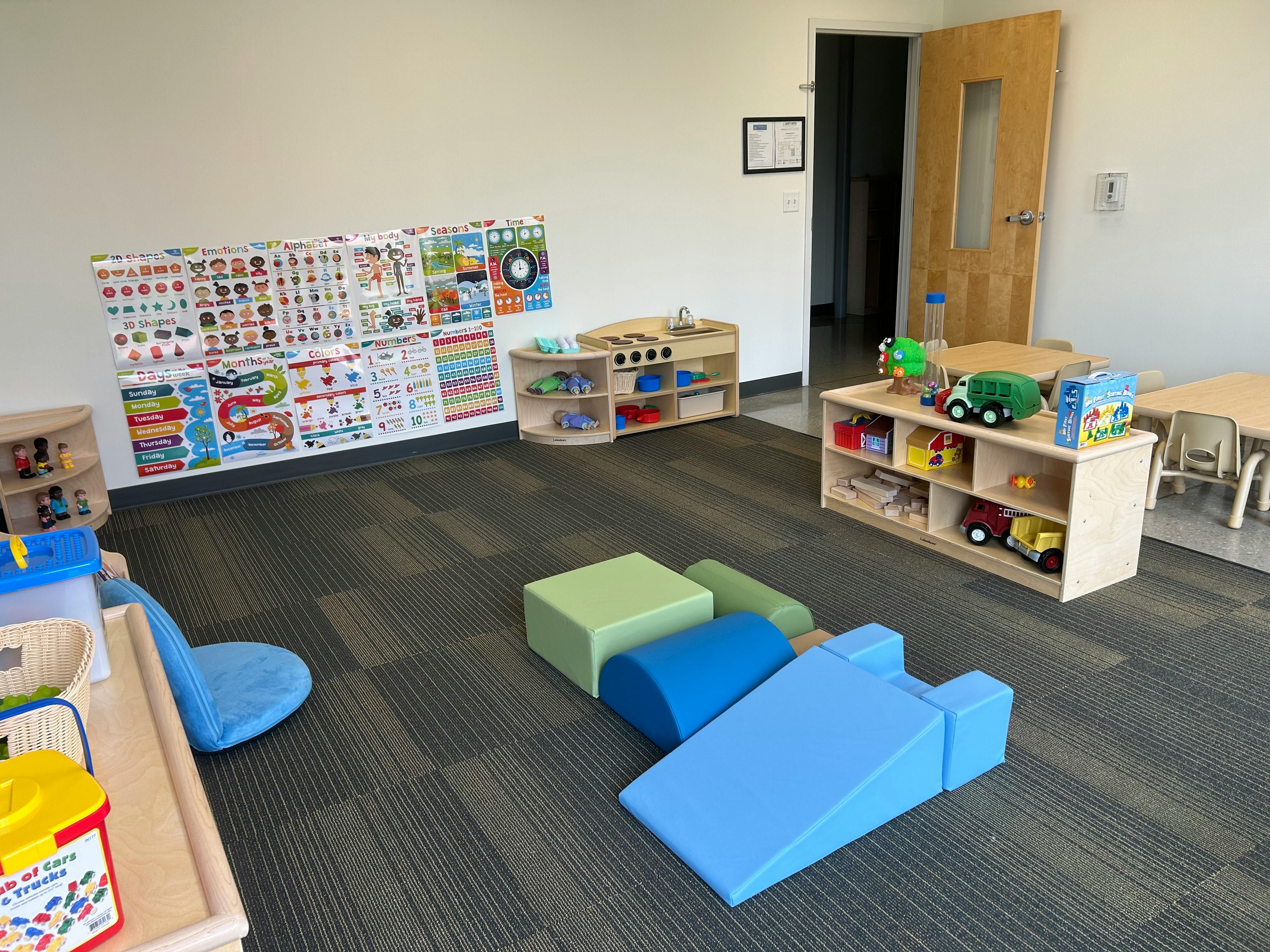 Playroom with soft play blocks, toy shelves, and educational posters