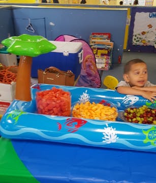 Child in an inflatable pool with snacks