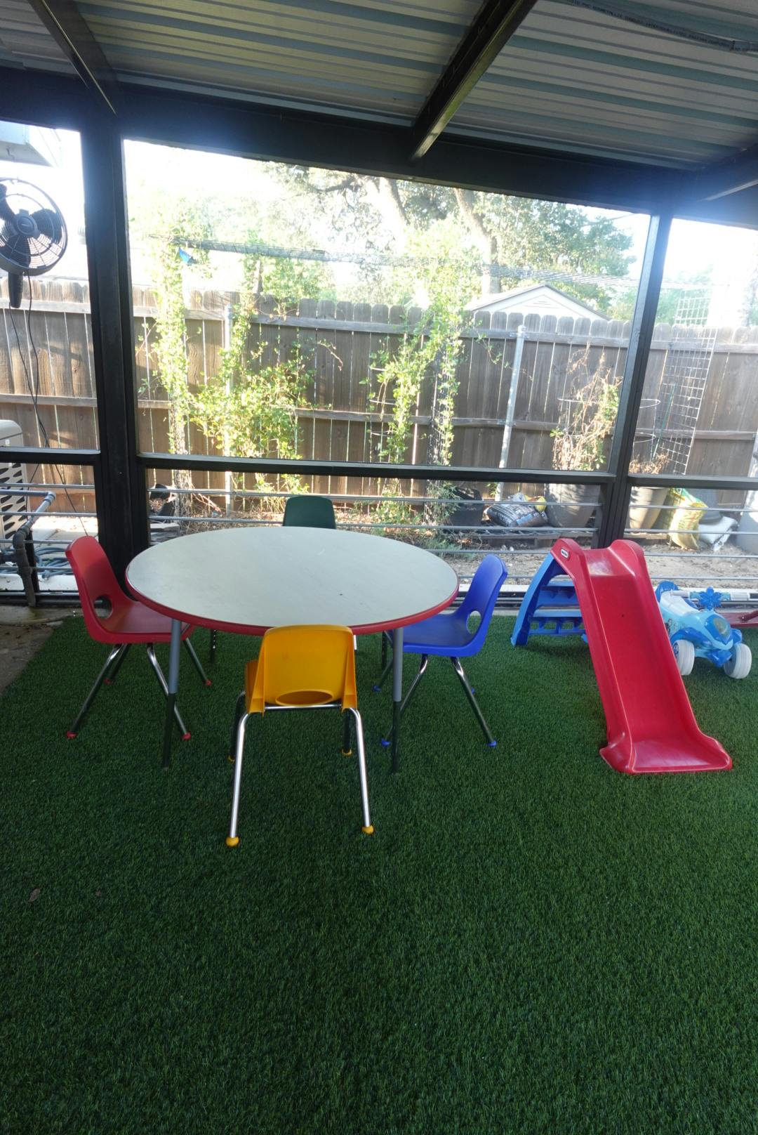 Children's table with chairs and a red slide on artificial grass