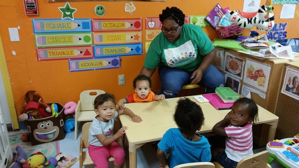 Person with three children at a small table in a classroom