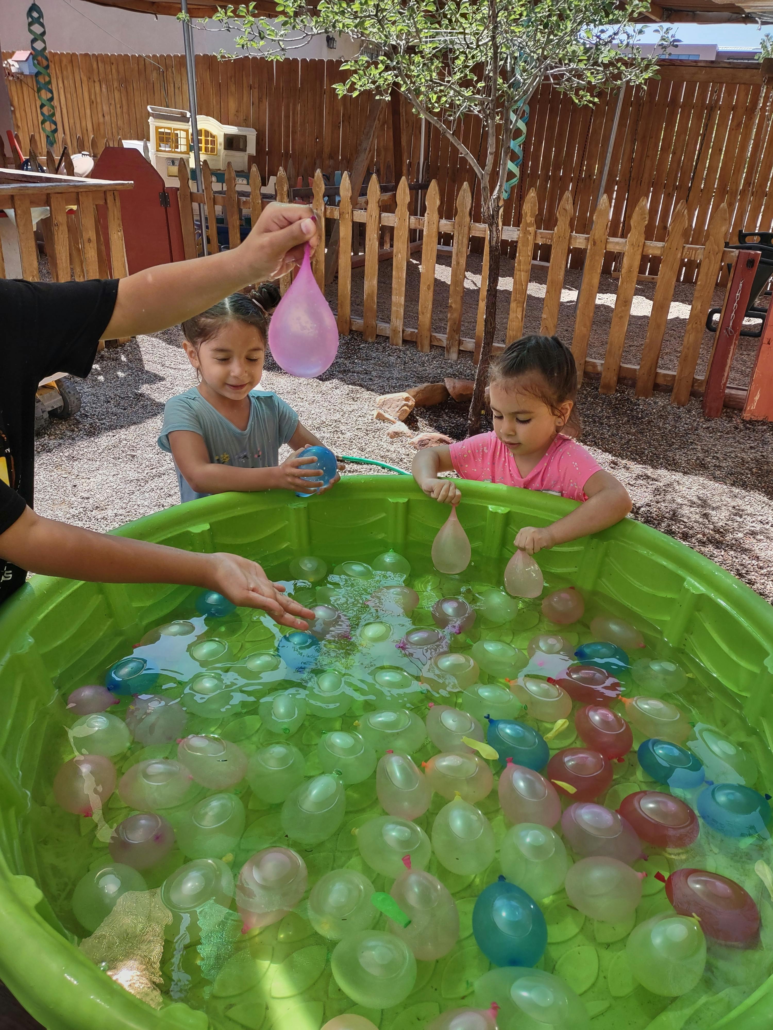 Children playing with water balloons in a plastic pool