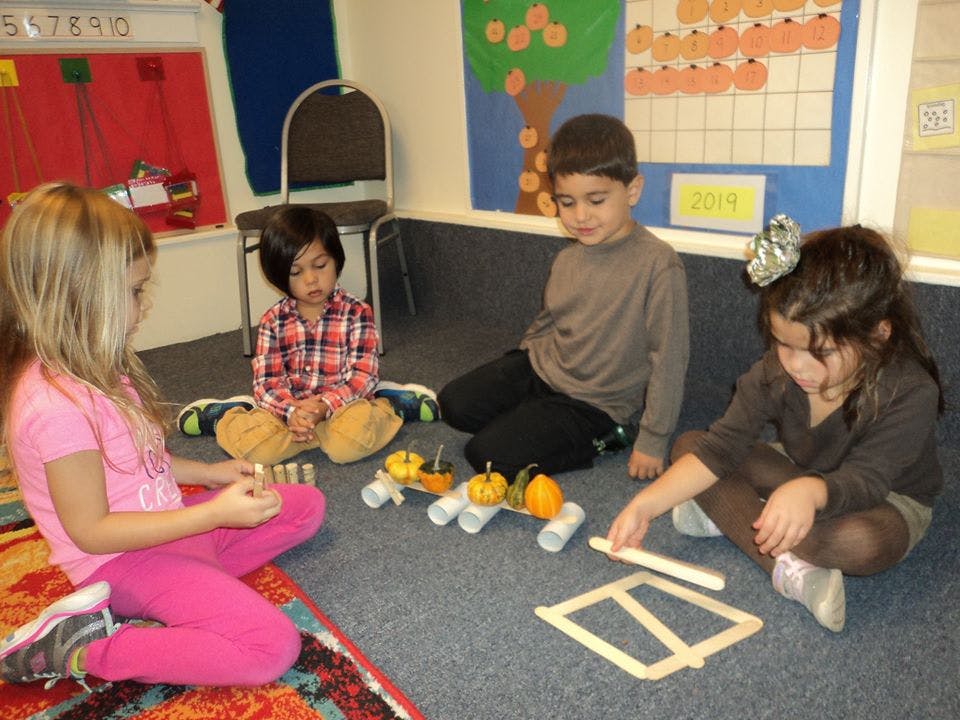 Four children sitting on the floor playing with craft materials